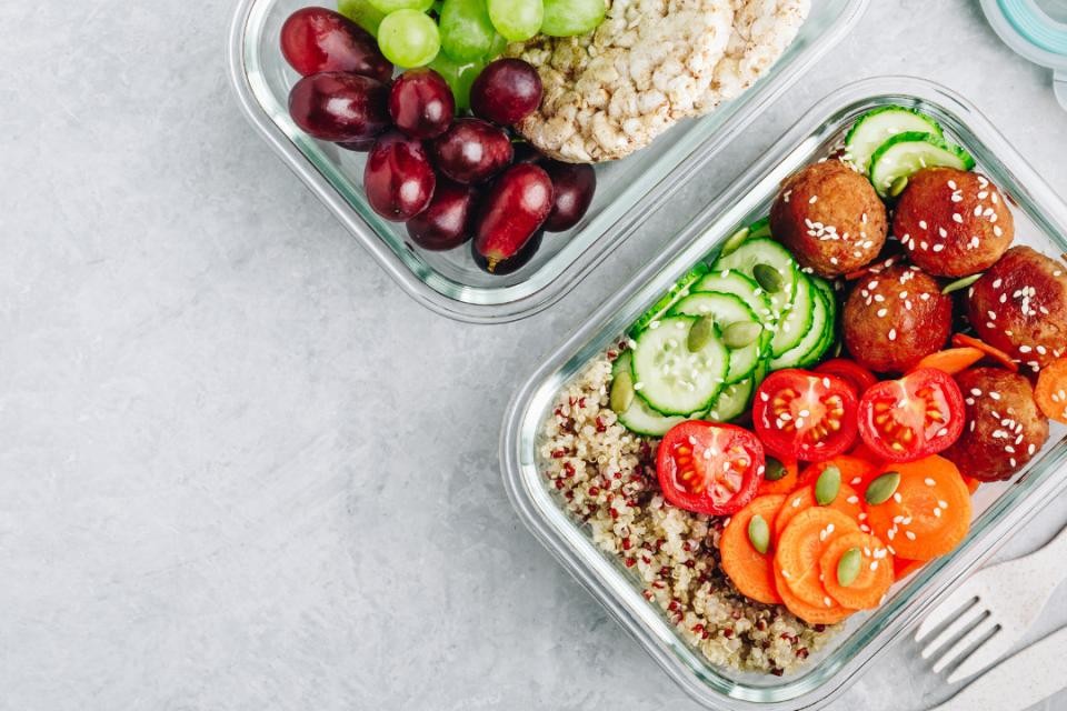 Grauer Untergrund. Darauf zwei Vesperdosen aus Glas mit Tomaten, Falafeln, Gurken und Reis enthalten.