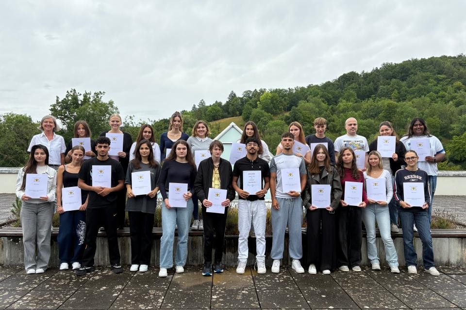 Schülerinnen und Schüler halten ihre Zeugnisse in den Händen