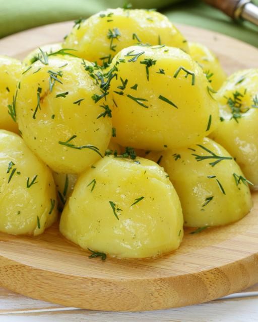 Auf dem Bild sieht man gestapelte und gewürzte Kartoffeln die auf einem runden Holzbrettchen liegen Auf dem Bild sieht man gestapelte und gewürzte Kartoffeln die auf einem runden Holzbrettchen liegen