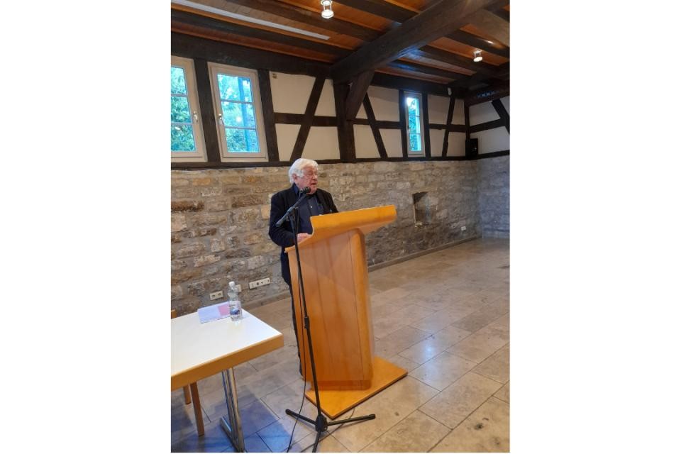 Braunes Rednerpult. Dahinter in schwarzem Anzug Herr Prod. Dr. Benz, der in ein schwarzes Mikrofon spricht.