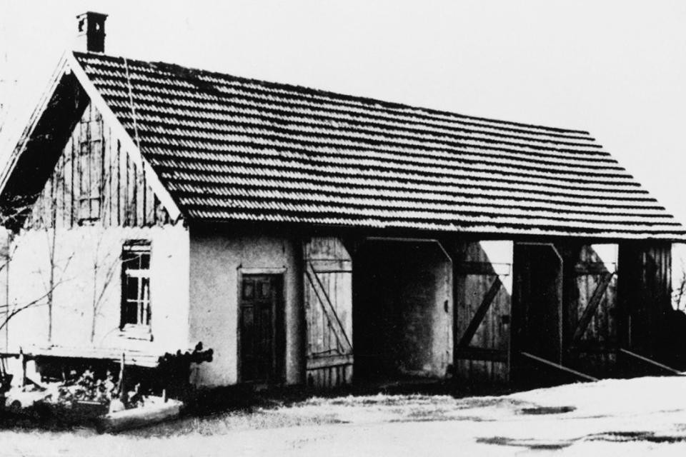Schwarz-weiß-Bild: Eine kleine Scheune mit mehreren Eingängen und einen Kamin.