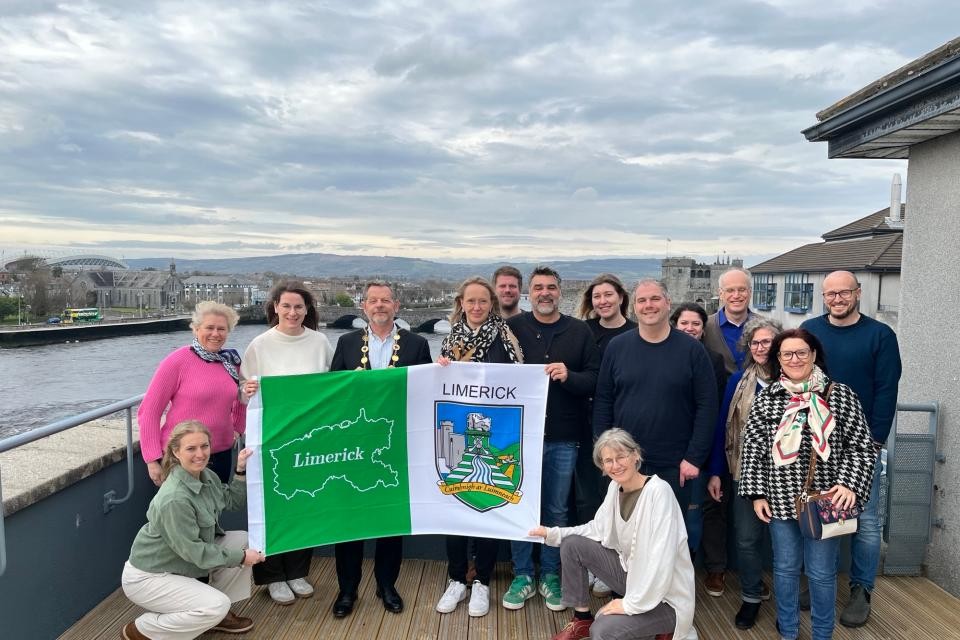 Nebeneinander stehen 15 Lehrerinnen und Lehrer, die eine grün-weiße Flagge halten.