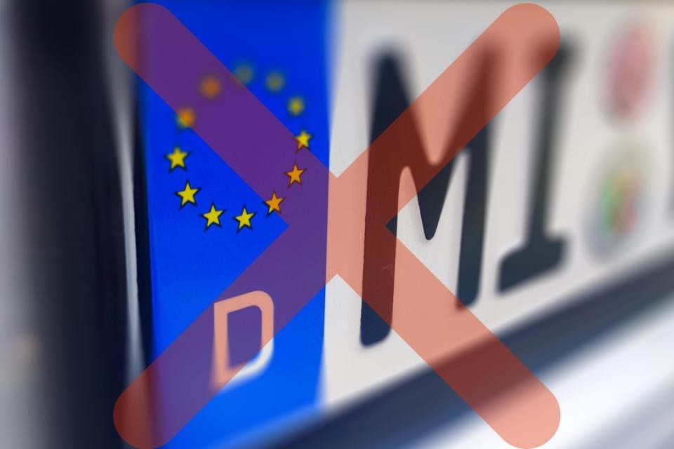 Deutsches KFZ-Kennzeichen mit leicht transparentem, rotem Kreuz davor.