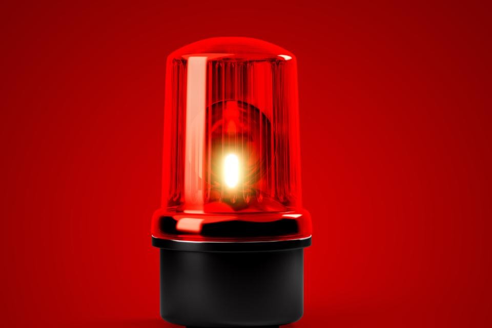Eine rot-schwarz blinkende Sirene auf rotem Hintergrund.