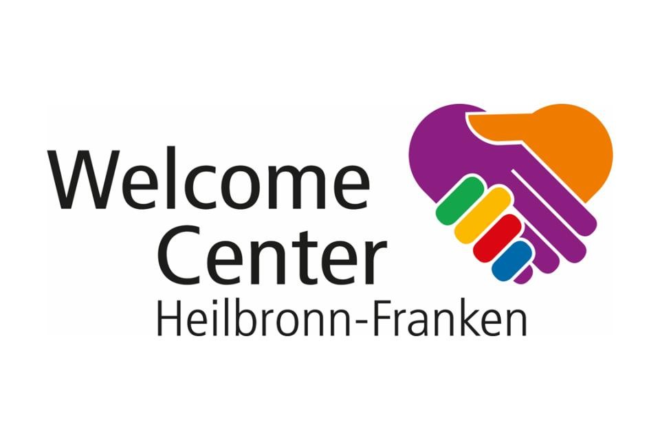 Logo des Welcome Centers Heilbronn- Franken. Schwarzer Schriftzug auf weißem Hintergrund: Welcome Center Heilbronn-Franken. Links Symbol von zwei Händen in orange, lila, grün, gelb, rot und blau.