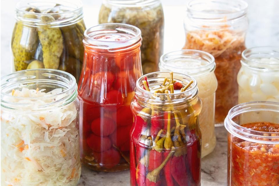 Verschieden gefüllte Einmachgläser mit roten, weißen und grünen Obst und Gemüse.