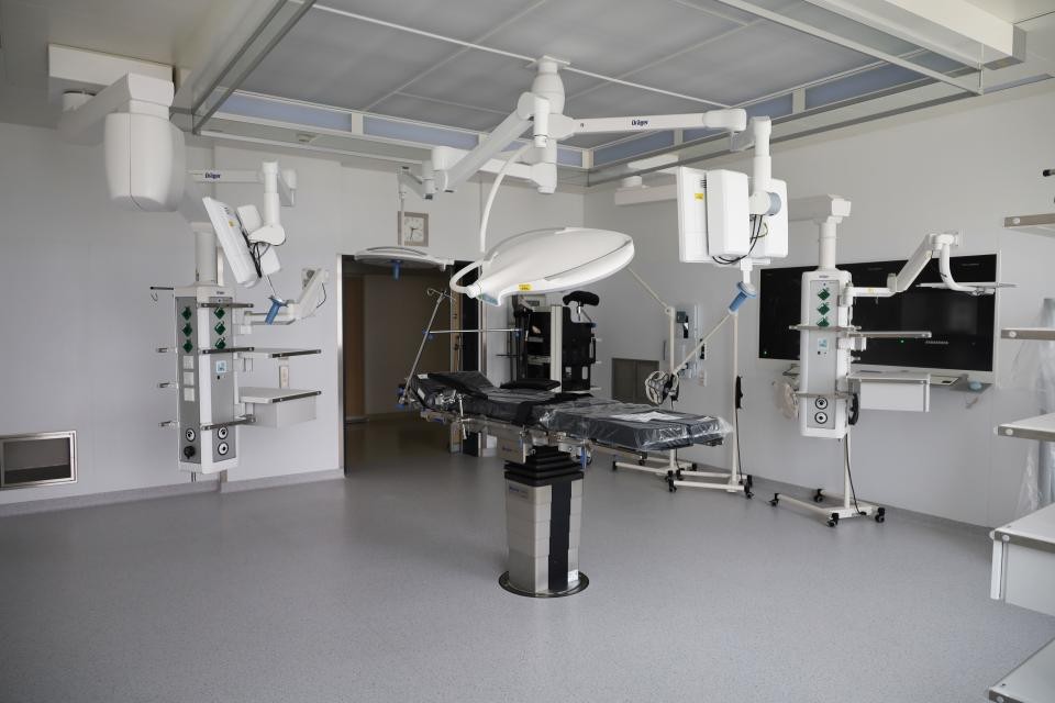 Verschiedene grau-weiße installierte moderene Geräte im Operationssaal. Im Hintergrund weiße Wände. Grauer Fußboden.