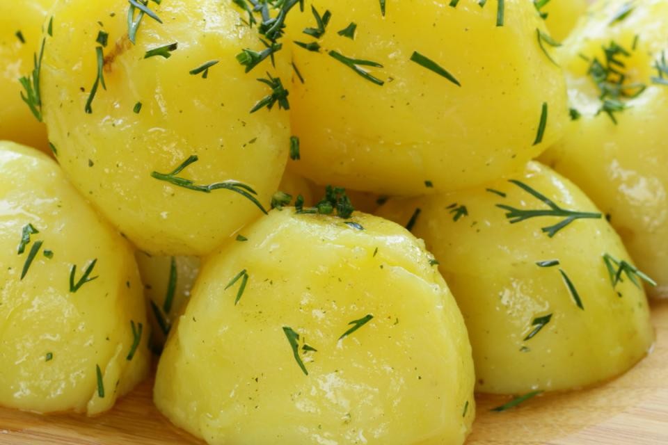 Auf dem Bild sieht man gestapelte und gewürzte Kartoffeln die auf einem runden Holzbrettchen liegen