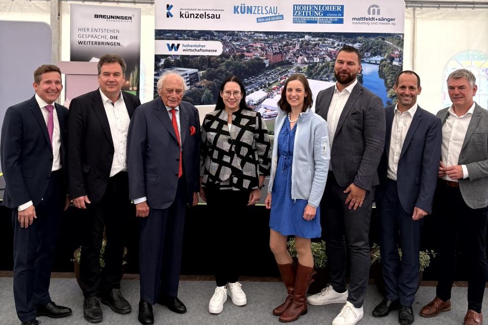Gruppenbild von 8 Personen bei der Eröffnung der Wirtschaftsmesse, im Hintergrund das Logo der Messe