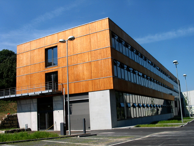 Auf dem Bild ist ein quaderförmiges Gebäude der Hochschule zu sehen. Der zweite und dritte Stock ist mit Holz verkleidet. 