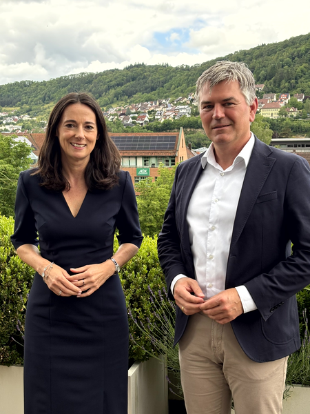 Katja Wennes und Landrat Schölzel. Im Hintergrund grüne Bepflanzung und bunte Häuser.