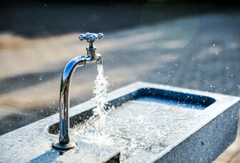 Wasser läuft aus einem Wasserhahn in ein Waschbecken aus Granit