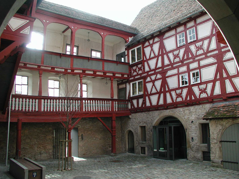 Innenhof eines alten Fachwerkhauses mit Torbogen und Balkon