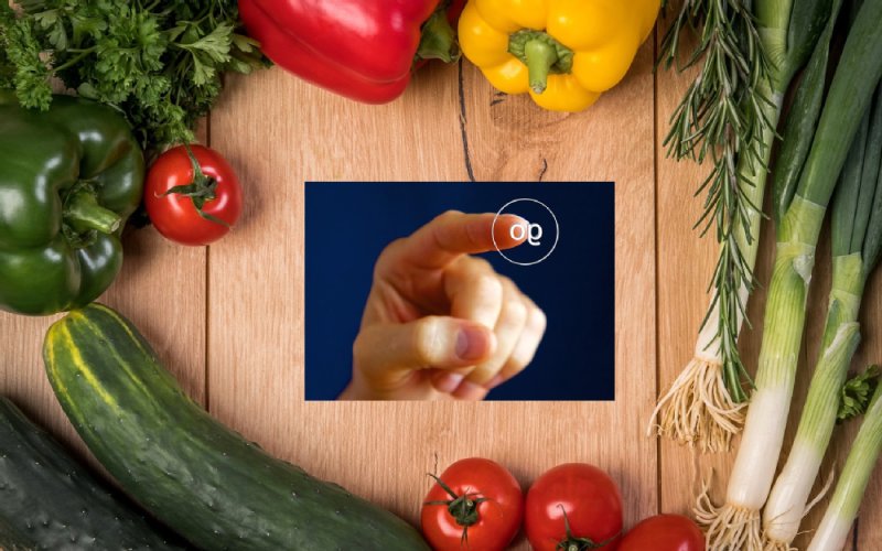 Am Rand schaut verschiedenes Obst und Gemüse ins Bild, darunter Gurke, Tomate, Paprika und Lauch. in der Mitte ist ein Bild mit einer Hand die auf einen Knopf drückt.